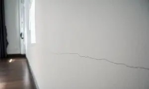 Pęknięcie na białej ścianie, widoczne w zbliżeniu.