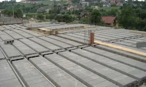 Budowa domu w toku. Na pierwszym planie widać ułożony strop strunobetonowy, a w tle malownicze wzgórza z zabudowaniami.