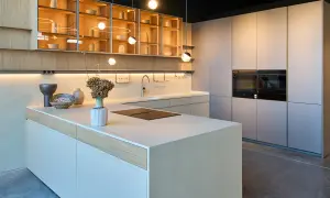 Cocina moderna con isla central, gabinetes de madera y acero inoxidable, y hornos integrados. Diseños cocinas minimalistas y elegantes.