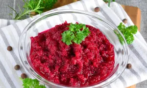 Ćwikła z chrzanem w szklanej misce, udekorowana natką pietruszki.