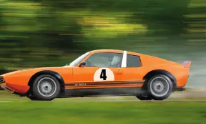 En orange Saab Sonett IV med nummer 4 på sidan susar fram på en bana, omgiven av suddiga gröna träd.