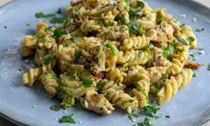 Pyszny makaron z brokułami, kurczakiem i suszonymi pomidorami, posypany parmezanem i natką pietruszki.