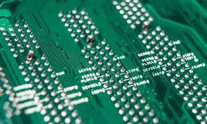 Zielona płyta drukowana z rzędami srebrnych pinów i oznaczeniami, świadectwo roli srebra w elektronice.