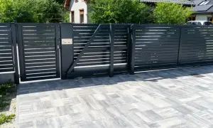 Nowoczesne, czarne ogrodzenie z automatyczną bramą. Czy ogrodzenie można odliczyć od podatku? Pytanie o inwestycję w bezpieczeństwo i estetykę posesji.