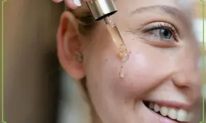 Kropla serum z pipety ląduje na policzku uśmiechniętej kobiety. To może być retinol, który pomaga w pielęgnacji skóry.