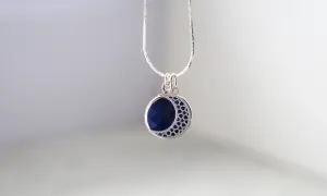Srebrny naszyjnik z zawieszką w kształcie półksiężyca z lapis lazuli i gwiazdkami.