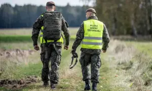 Dwóch żołnierzy Wojsk Obrony Terytorialnej w kamizelkach odblaskowych idzie przez pole. Rezygnacja z WOT może mieć poważne konsekwencje.