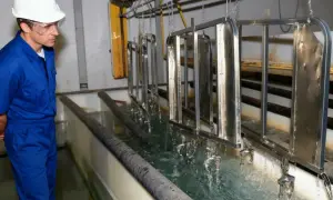 Pracownik w galwanizerni nadzoruje proces zanurzania metalowych elementów w kąpieli. To właśnie galwanizernia, gdzie metale zyskują ochronną powłokę.