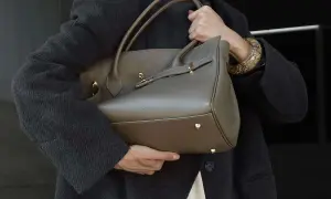 Elegancka, szara torebka z wysokiej jakości skóry, idealna dla miłośniczek luksusowych marki torebek. Złote okucia dodają jej blasku.