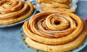 Churros dorados y azucarados en espiral en platos.