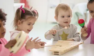 Kinder unter 3 Jahren musizieren fröhlich mit Xylophon und Maracas.
