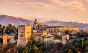 Die Alhambra in Granada, ein Ort voller Geschichte und **Granada Geheimtipps**, thront vor schneebedeckten Bergen.