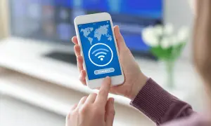 Dłoń trzyma smartfon z mapą świata i ikoną Wi-Fi. Dotyka przycisku "CONNECT", szukając darmowego hotspotu.