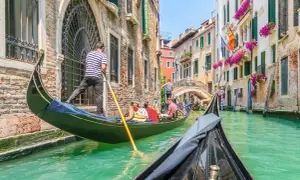 En gondoltur i Venedig är en dröm för många. Undrar du vad kostar det att åka gondol i Venedig? Här ser du en gondol som glider fram på kanalen.