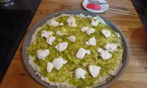 Une pizza à la pâte fine, recouverte de sauce verte et de morceaux de fromage blanc. Un délice inspiré du pain sarde.