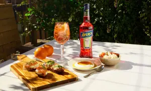 En Aperol Spritz med tilltugg till aperol spritz: laxsnittar, ost med honung och inlagda grönsaker.