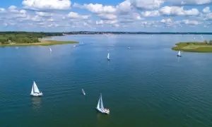 Segelboote auf dem Wasser in Masuren, Polen. Ein sonniger Tag mit Wolken, ideal zum Segeln.