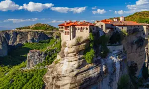 Meteora Kloster, ein atemberaubendes Bauwerk auf Felsen, thront majestätisch über einer grünen Schlucht.