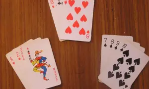 Na stole leżą karty: joker, dwójka i as, a także cztery ósemki i sekwencja pikowa od 7 do 10.