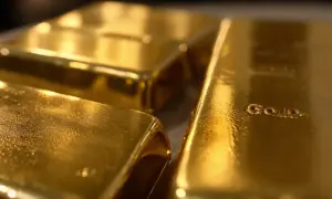 Trzy błyszczące sztabki złota, jedna z napisem "GOLD".