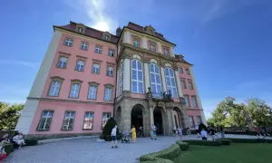 Zamek Książ, malowniczo położony, łatwy dojazd PKP. Turyści zwiedzają barokową budowlę w słoneczny dzień.