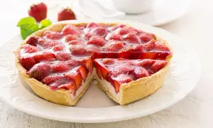 Ein saftiger Erdbeerkuchen mit Quarkfüllung, bedeckt mit frischen Erdbeeren und glänzendem Tortenguss. Ein Stück ist bereits entnommen.