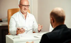 Lekarz w białej koszuli prowadzi psychoterapię dynamiczną, gestykulując i patrząc na pacjenta.