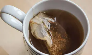 Kubek z czarną herbatą i torebką. Choć ma wiele zalet, czarna herbata właściwości negatywne też posiada, np. może powodować bezsenność.