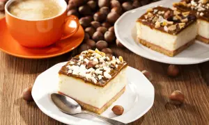 Ein Stück cremiger Käsekuchen mit Schokoladenglasur und Nüssen, dazu eine Tasse Kaffee. Perfekt für einen schnellen Kuchengenuss.