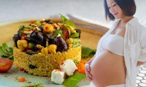 Piatto colorato di cous cous con verdure e formaggio, accanto a una donna incinta. Un pasto nutriente per la gravidanza.