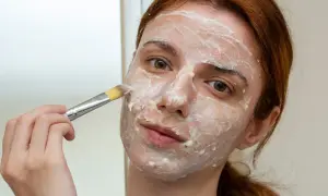 Dziewczyna nakłada pędzlem naturalną maseczkę na twarz, eksperymentując z domowymi sposobami na piękno.
