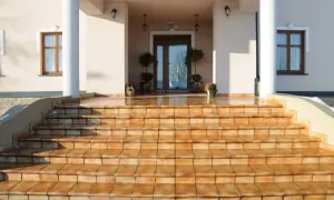 Amplias escaleras de entrada a un chalet, con escalones de baldosas naranjas que brillan bajo el sol.