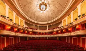 Wnętrze teatru z czerwonymi fotelami i bogato zdobionym sufitem, gotowe na wspaniały performance.