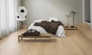 Sovrum med en säng, en bänk och en unik lampa. Olika golv i olika rum skapar en varm och inbjudande atmosfär.