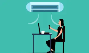 Une femme ajuste la climatisation pour une température idéale au bureau, profitant d'un environnement de travail confortable.