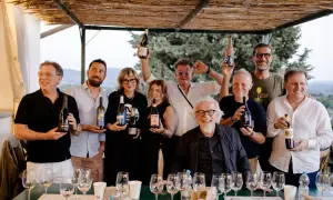 Un gruppo di persone sorridenti, alcuni con bottiglie di vino, celebra i papi marchigiani.