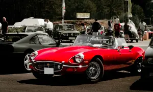 Roter Oldtimer-Cabriolet glänzt auf einem Treffen in Berlin. Im Hintergrund weitere Klassiker und Besucher.