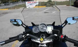 Widok z motocykla: przedłużenie lusterek motocyklowych, deska rozdzielcza z prędkościomierzem i obrotomierzem.