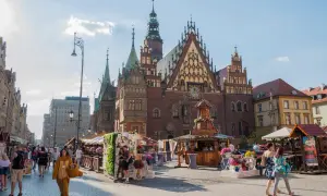 Tętniący życiem Rynek we Wrocławiu, z pięknym Ratuszem i kramami pełnymi kwiatów. Wspaniałe wrocławskie atrakcje w letnim słońcu.