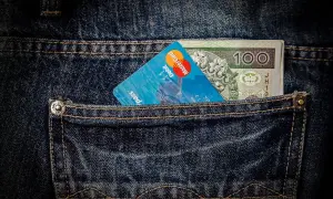 Karta płatnicza i banknot 100 zł w tylnej kieszeni dżinsów. To nowoczesna waluta, gotowa na podróż na Bali.