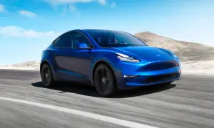 Blå Tesla Model Y kör på en väg i ökenlandskap. En dröm om en tesla till salu.