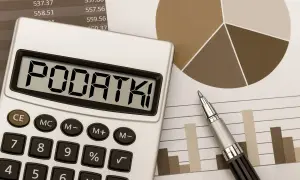 Kalkulator z napisem "PODATKI" na tle wykresów i tabel. Obliczanie podatku od sprzedaży nieruchomości.
