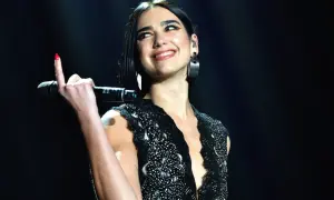 Uśmiechnięta Dua Lipa z mikrofonem w dłoni, podczas jednego ze swoich ekscytujących koncertów.