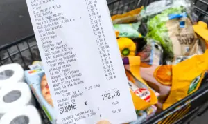 Kassenbon mit vielen Produkten, Einkaufswagen im Hintergrund. Die Digitalisierung im Handel wird durch solche Belege und die Möglichkeit zur digitalen Erfassung von Einkäufen sichtbar.