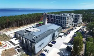 Nowoczesny aquapark i hotel nad morzem, idealne na tanie miejscowości nad morzem. Widać zjeżdżalnie, baseny i parking.