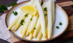 Frischer weißer Spargel, perfekt gekocht, garniert mit Petersilie und einer Zitronenspalte auf einem Teller. Ein Genuss, wenn Spargel Saison hat.