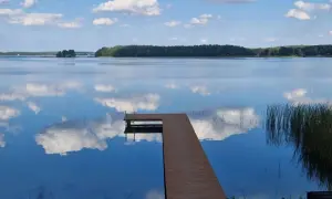 Drewniany pomost na spokojnym jeziorze przechlewskim, odbijającym błękitne niebo z białymi chmurami.