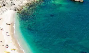 Spiaggia dorata e mare cristallino, con kayak gialli e persone che si godono il sole. Un angolo di paradiso che ricorda il **gradara mare**.