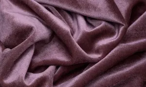 Miękka, fioletowa tkanina z meszkiem, układająca się w eleganckie fałdy.