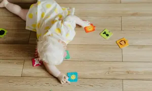 Dziecko z jasnymi włosami leży na podłodze, otoczone kolorowymi puzzlami ze zwierzątkami. Zastanawiasz się, dlaczego dziecko buczy? Może nie może dopasować puzzla z uśmiechniętym słoneczkiem.